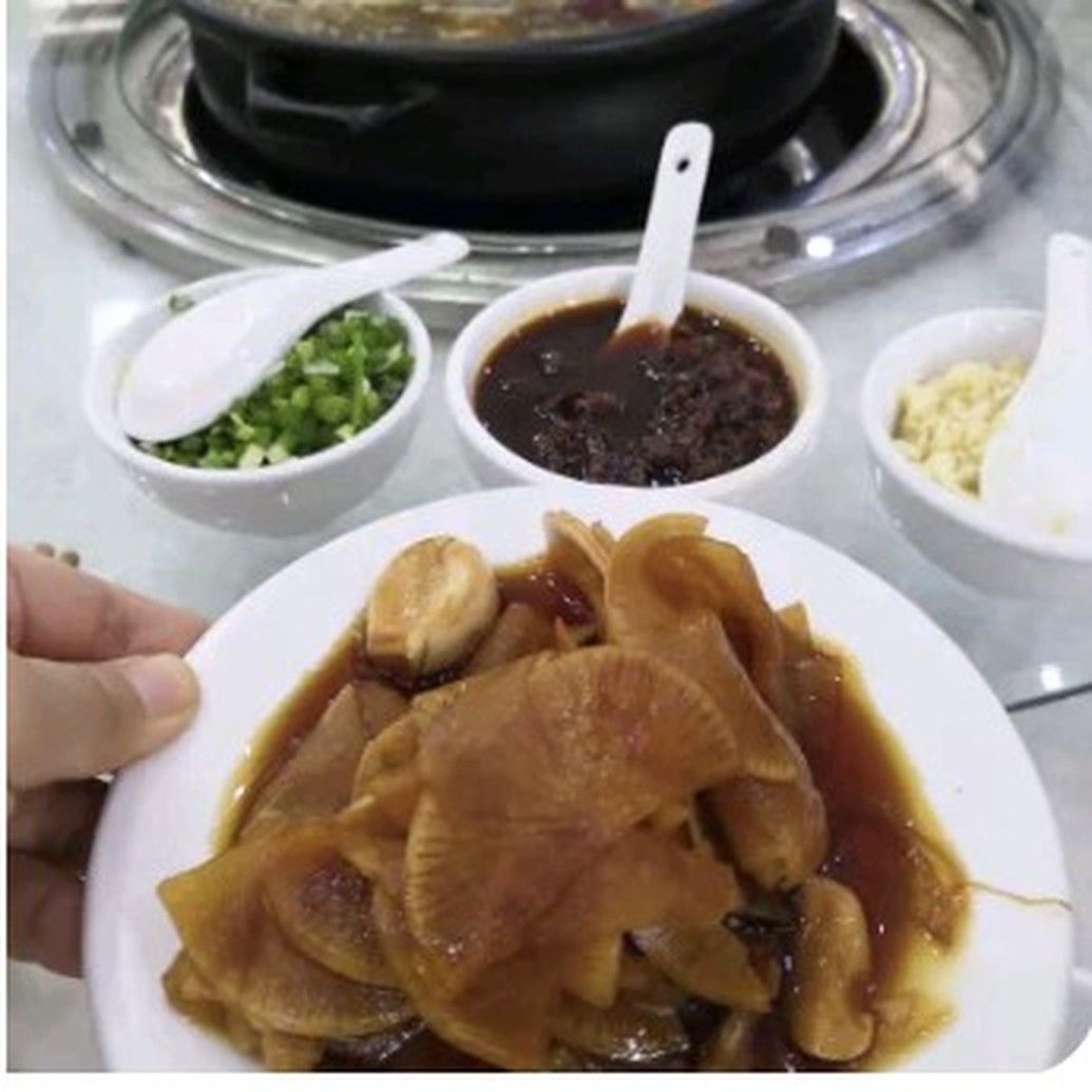 手拿一盘酸甜味萝卜特写，配蘸碟与葱花，色泽红亮